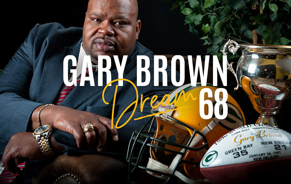 Gary Brown poses confidently with a trophy and football gear, showcasing his achievements and dreams.