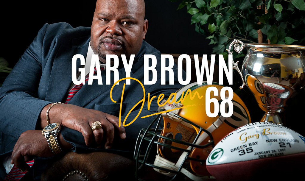 Gary Brown poses confidently with a trophy and football gear, showcasing his achievements and dreams.