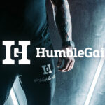 Close-up of a person wearing black Humble Gainz joggers and a sleeveless top under neon lights.