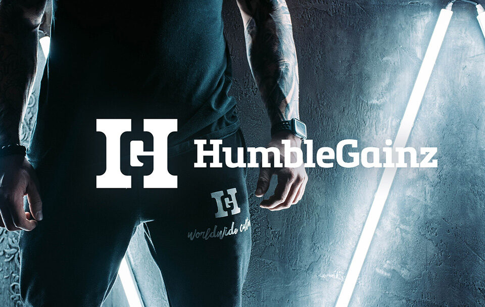 Close-up of a person wearing black Humble Gainz joggers and a sleeveless top under neon lights.