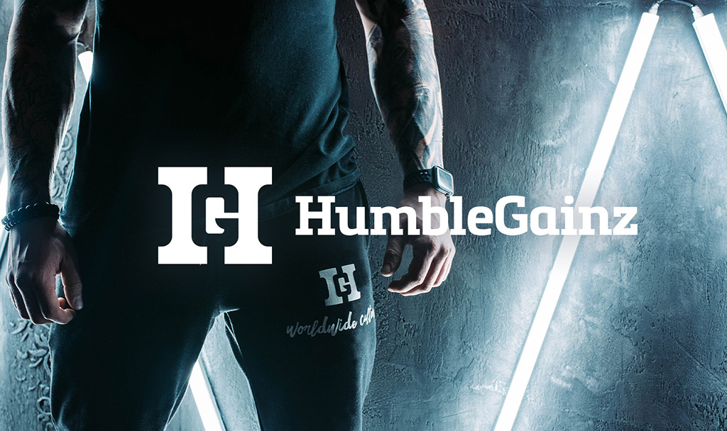 Close-up of a person wearing black Humble Gainz joggers and a sleeveless top under neon lights.