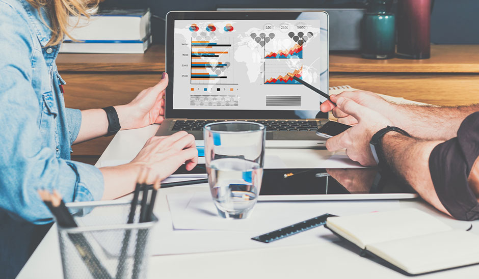 Individuals analyzing digital marketing data on a laptop with graphs and charts.