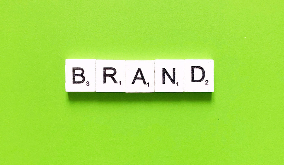 Scrabble tiles spelling the word 'BRAND' on a vibrant green background.