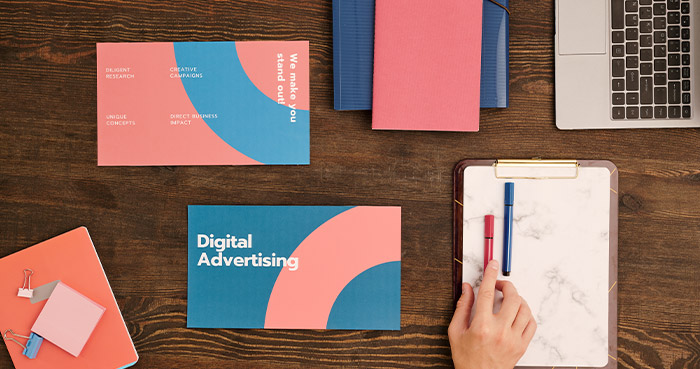 An overhead view of a workspace featuring marketing materials, a laptop, and stationery.