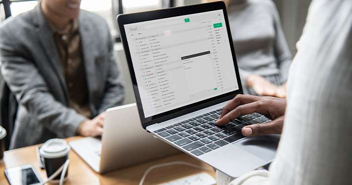 Person using a laptop to manage an email campaign in a meeting environment.