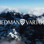 Aerial view of snow-capped mountains with clouds and the Friedman Vartolo logo overlayed.