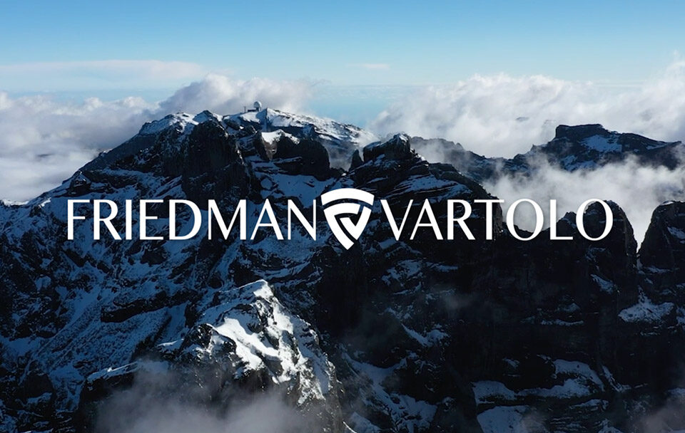 Aerial view of snow-capped mountains with clouds and the Friedman Vartolo logo overlayed.