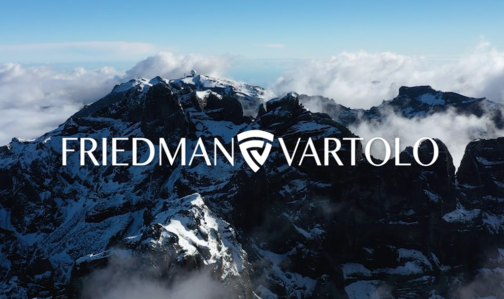 Aerial view of snow-capped mountains with clouds and the Friedman Vartolo logo overlayed.