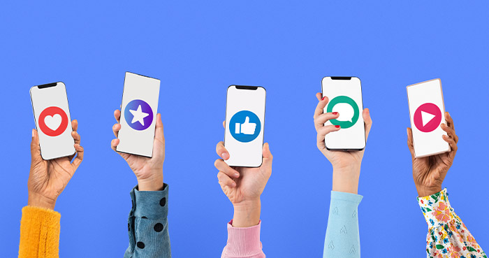 Diverse hands holding smartphones displaying various social media icons on a blue background.