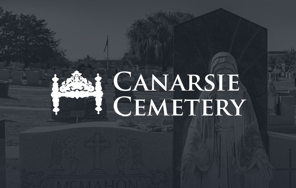 Gravestones and a statue in Canarsie Cemetery with the cemetery name prominently displayed.