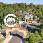 Aerial view of Cypress Hills Cemetery entrance surrounded by trees and gravestones.