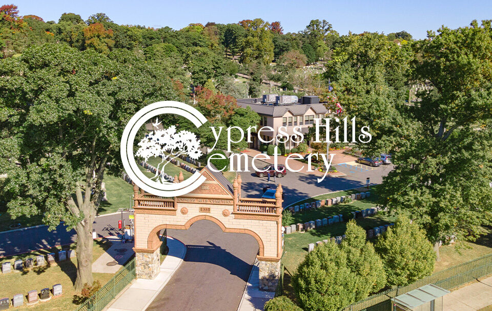 Aerial view of Cypress Hills Cemetery entrance surrounded by trees and gravestones.