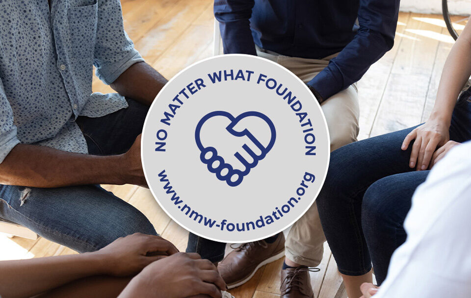 Group of people with a circular logo for No Matter What Foundation featuring a handshake.