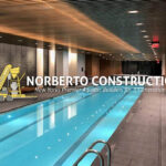 Modern indoor swimming pool by Norberto Construction featuring wooden paneling and a sleek design.