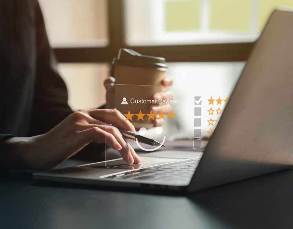 Person typing on a laptop with a coffee cup, focused on customer reviews.