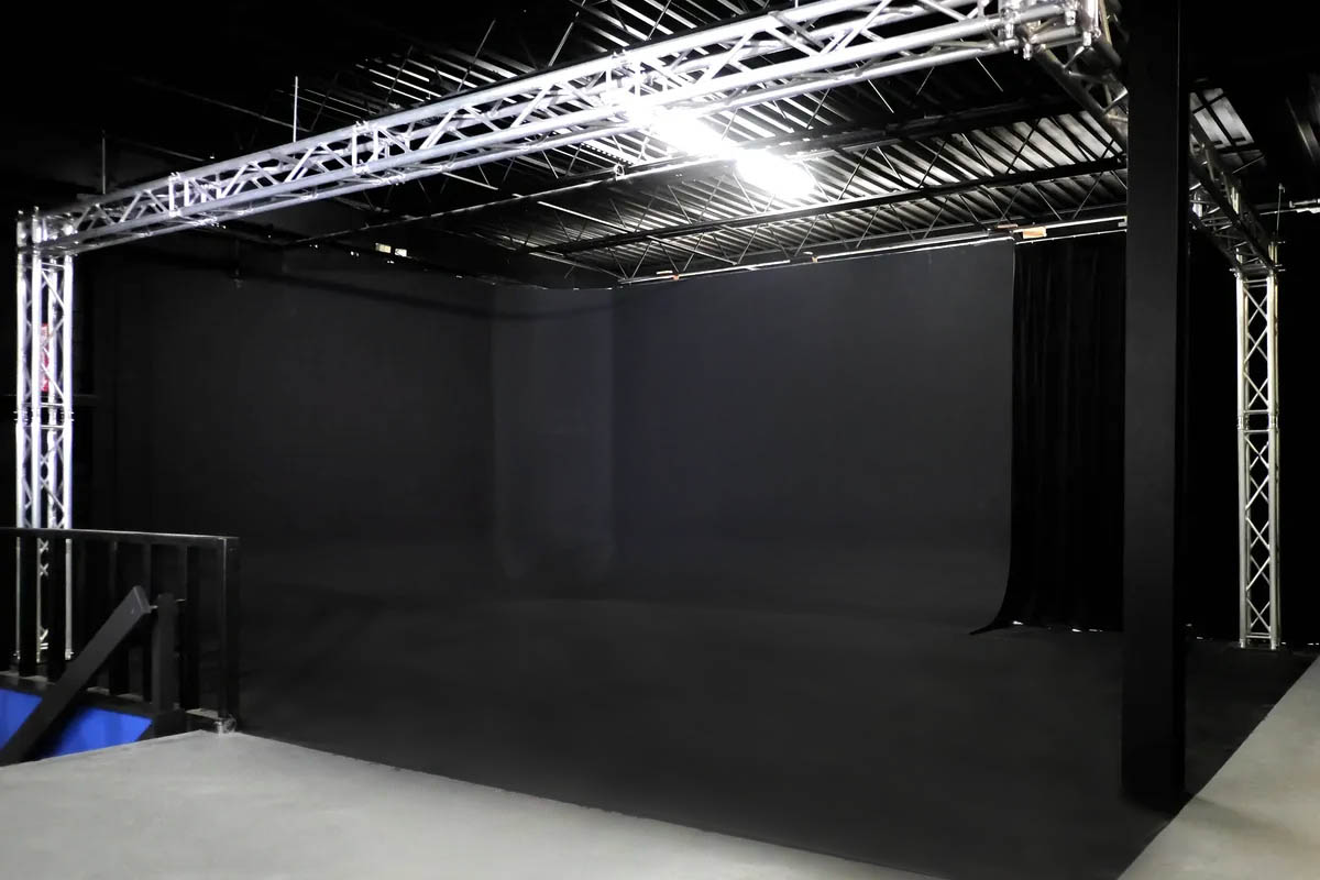 Black Cycs | Idea Stream Marketing A spacious photography studio with black backdrop and metal truss structure.