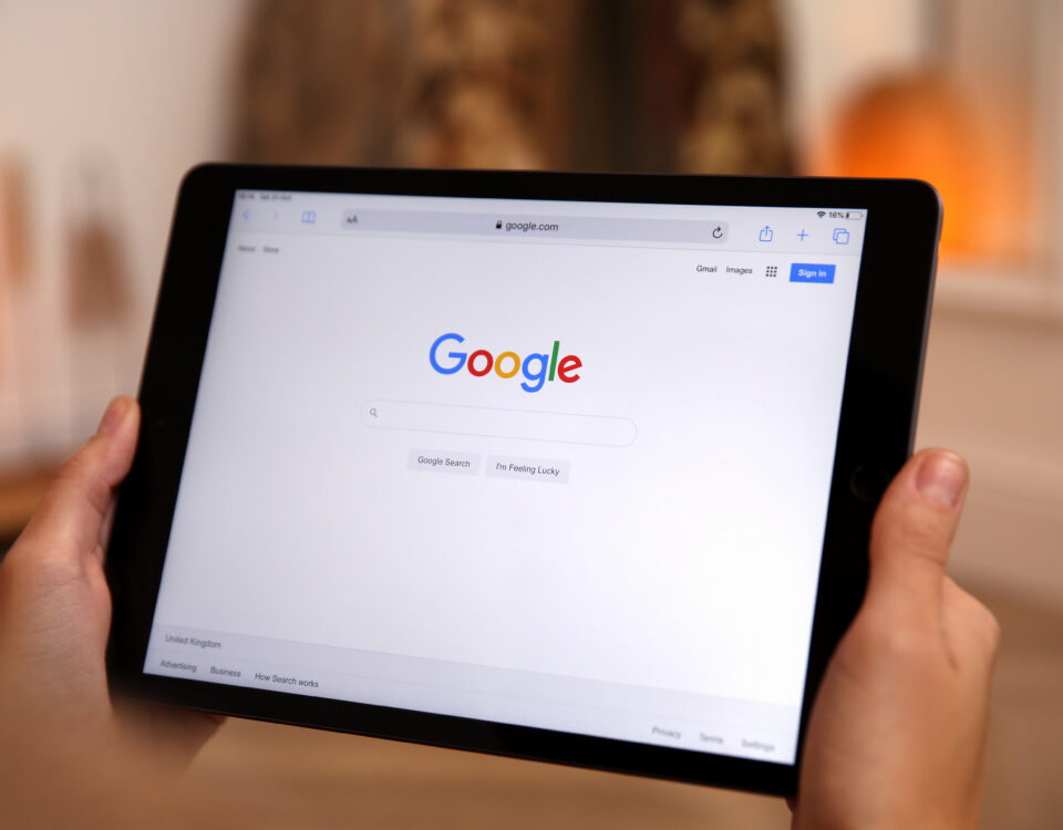 A person holding a tablet displaying the Google search homepage.