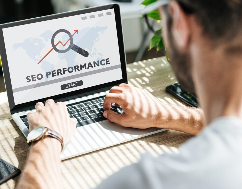 Developer working on laptop displaying SEO performance metrics with a magnifying glass overlay.