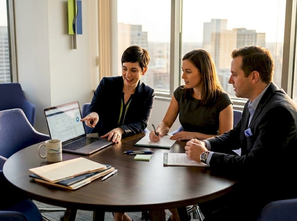 Three attorneys discussing a digital marketing plan in a modern office setting.