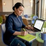 Restaurant owner reviewing marketing analytics on a laptop in a bright café.