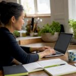 Businesswoman Coding in Home Office | Idea Stream Marketing Businesswoman programming on a laptop in a cozy home office with plants.