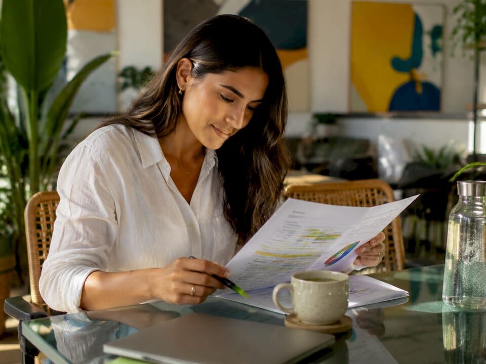 Woman reviewing a content strategy document at a glass table with plants around.