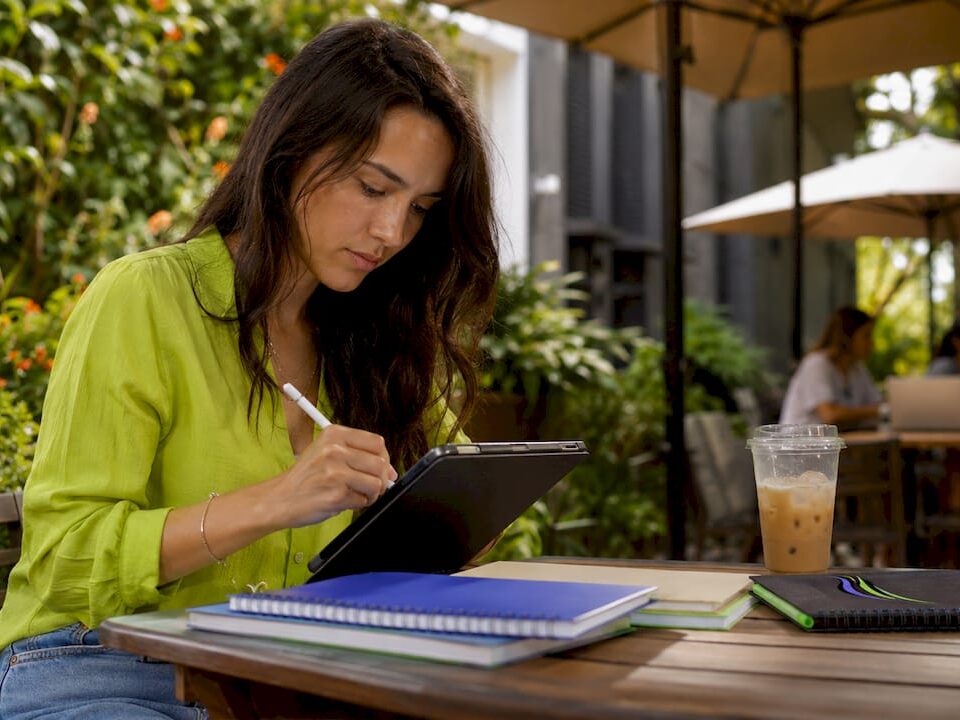 Female social media manager planning workflow using a tablet in an outdoor coworking space.