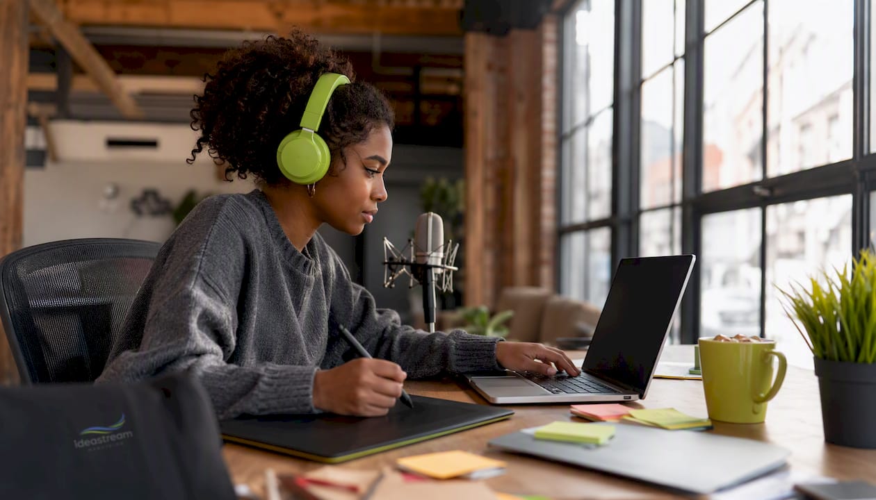 A young woman in headphones engaged in video editing at a desk with a laptop and colorful notes.