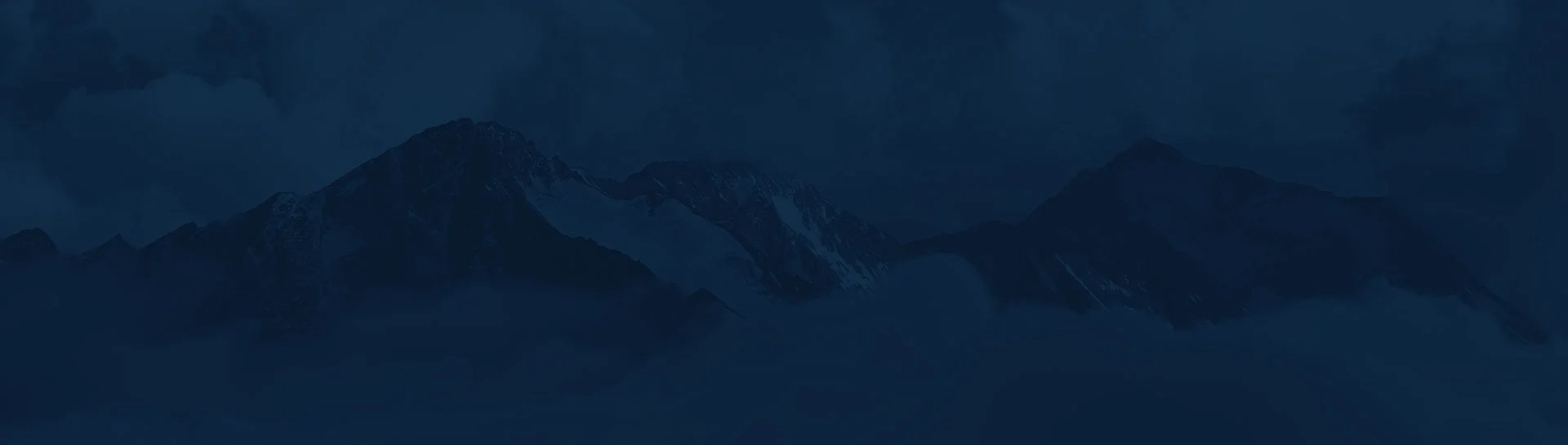 Dark mountain landscape with cloudy sky and snow-capped peaks