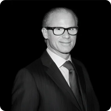 Professional man in a suit and glasses posing against a dark background.