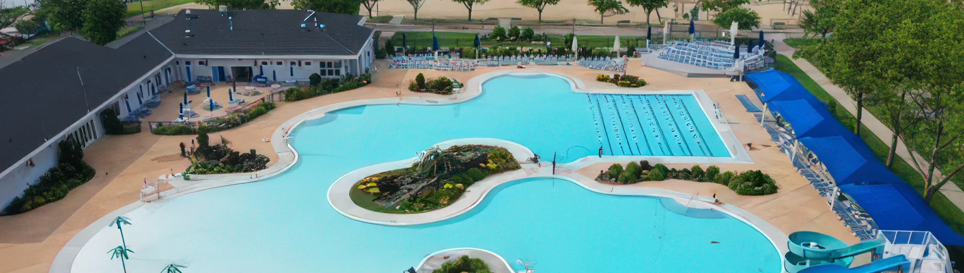 Aerial view of a large swimming pool area with lounge chairs and palm trees.